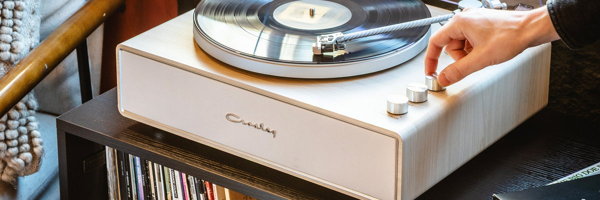 A woman browsing records beside a Crosley turntable and speakers