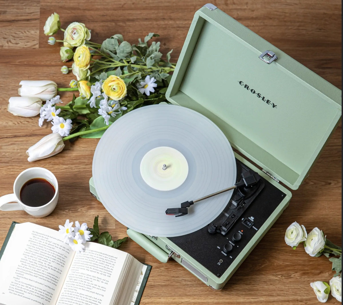 Crosley record player beside flowers and a cup of coffee