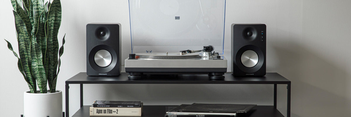 Crosley turntable and stereo speakers displayed on a media stand